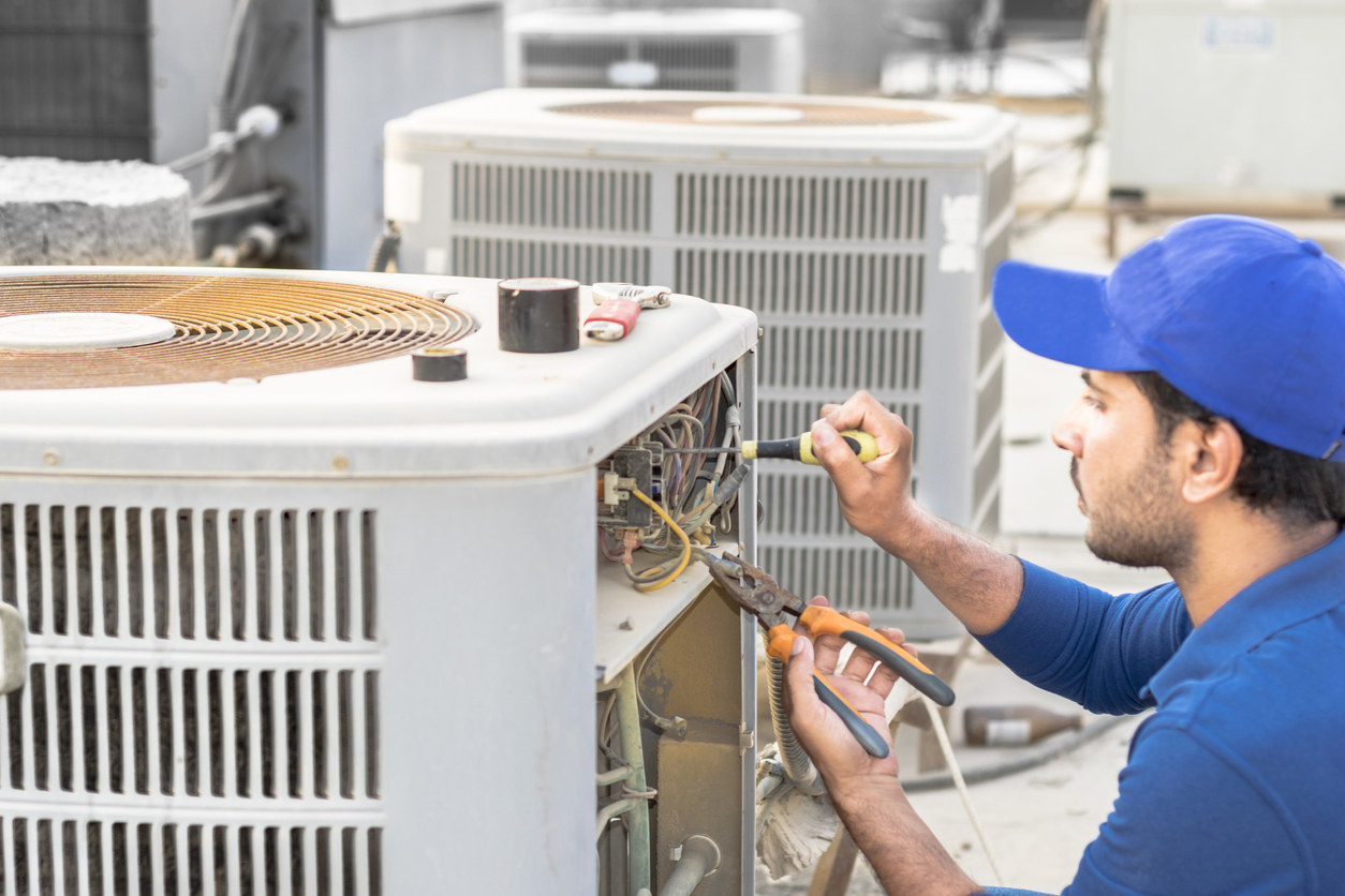 hvac technician repairs an air conditioning unit on a rooftop