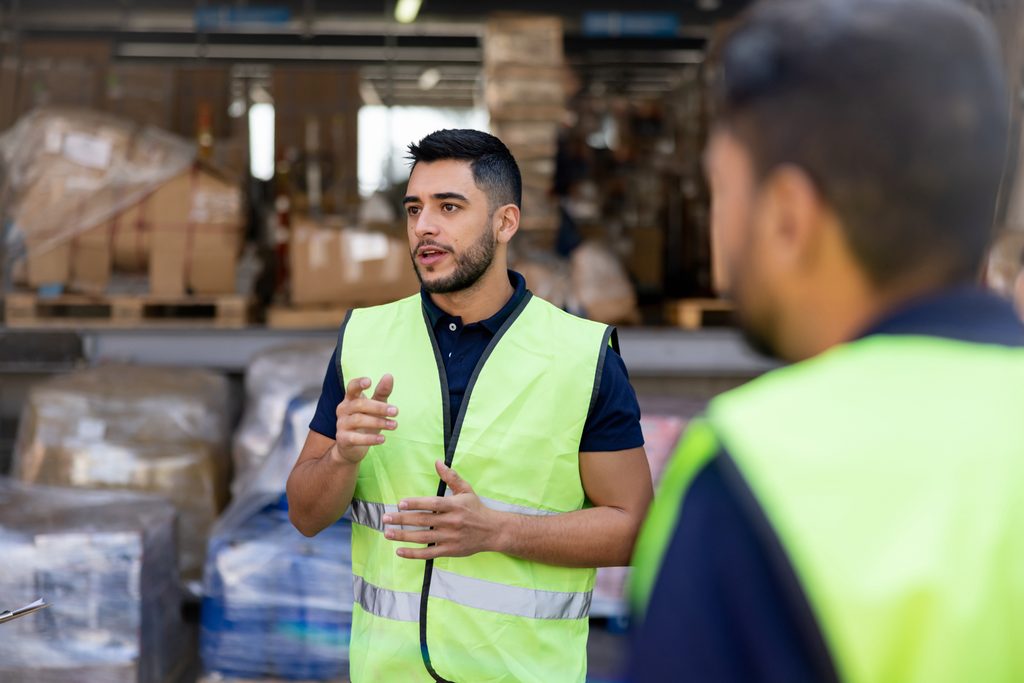 Worker talking to a group of coworkers at a distribution warehouse